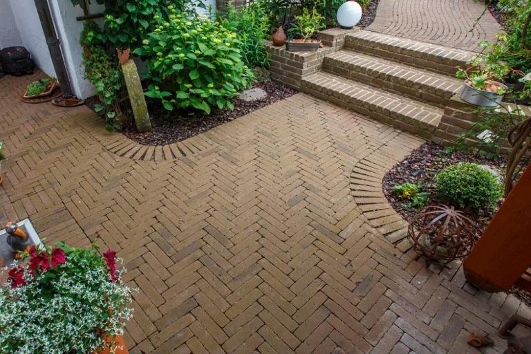 Gepflasterter Gartenbereich mit Stufen und Pflanzen, gepflegte Gartengestaltung von Bella Flora GmbH.