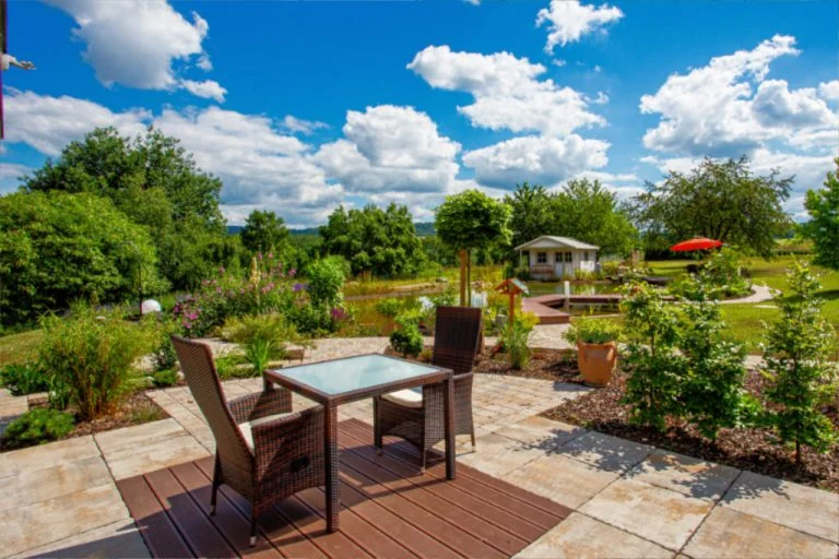 Hochwertiger Gartentisch und Stühle auf Terrasse mit Blick ins grüne Gartengelände.