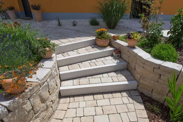 Gepflasterte Treppenanlage mit Blockstufen, Natursteinmauern und integrierter Bepflanzung, Garten- und Landschaftsbau in Hirschaid von BELLA FLORA GmbH.