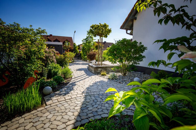 Geschwungener Gartenweg aus Kleinsteinpflaster mit Hochbeet und strukturierter Bepflanzung, Gartenweg anlegen in Heroldsbach von BELLA FLORA GmbH.