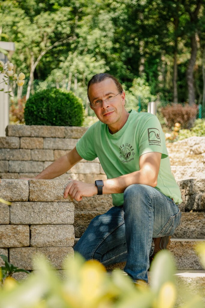 Mitarbeiter von BELLA FLORA GmbH sitzend auf Naturstein-Stufenanlage in hochwertig gestaltetem Garten im Garten- und Landschaftsbau in Fränkische Schweiz von BELLA FLORA GmbH.