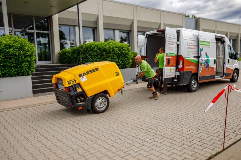 Anlieferung und Positionierung eines mobilen Kompressors für Bodeninjektion und Bodenbelüftung auf befestigter Fläche im öffentlichen Raum in Hausen von BELLA FLORA GmbH.
