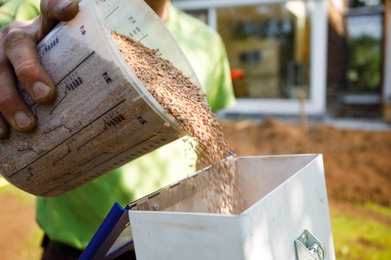 Einfüllen von Rasendünger-Granulat in einen Streuwagen zur Bodenverbesserung bei Gartenanlage in Forchheim von BELLA FLORA GmbH.