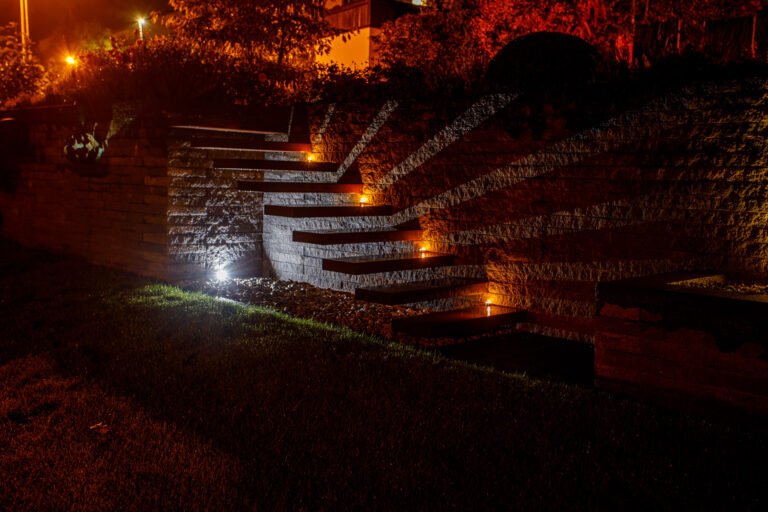 Beleuchtete Treppenanlage aus Betonstein mit integrierter Stufenbeleuchtung in massiver Gartenmauer bei Nacht, Treppenbau und Gartenbeleuchtung in der Fränkischen Schweiz von BELLA FLORA GmbH.