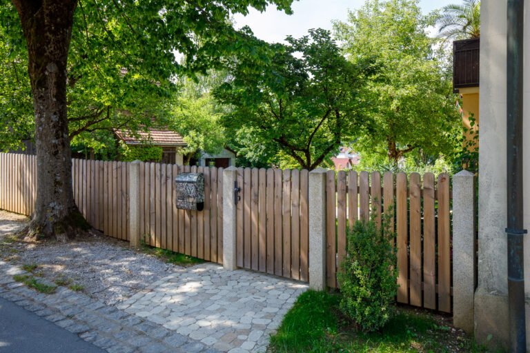 Holzzaun mit integrierter Gartentür und massiven Natursteinpfosten als Grundstückseinfassung, Zaunbau im Gartenbereich in Eggolsheim von BELLA FLORA GmbH.