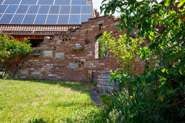 Historische Ziegel-Gartenmauer mit Natursteinelementen und Rundbogen im Gartenbereich, Gartenmauer bauen in Bamberg von BELLA FLORA GmbH.