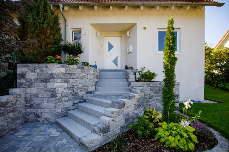 Hauseingang mit geradläufiger Granittreppe, Betonstein-Stützmauern und Pflasterpodest, fachgerechte Eingangs- und Treppenanlage in Forchheim von BELLA FLORA GmbH.