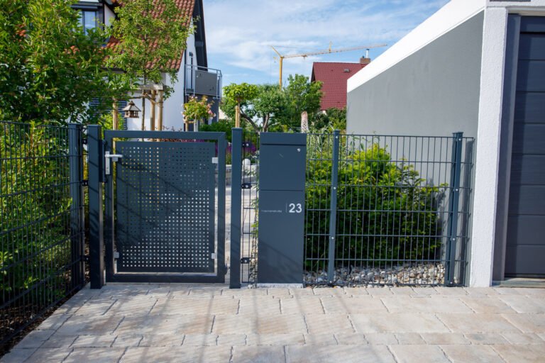 Moderne Metallzaunanlage mit integriertem Gartentor, Briefkastenstele und Pflasterzugang vor Einfamilienhaus, Zaunbau und Vorgartengestaltung in Heroldsbach von BELLA FLORA GmbH.