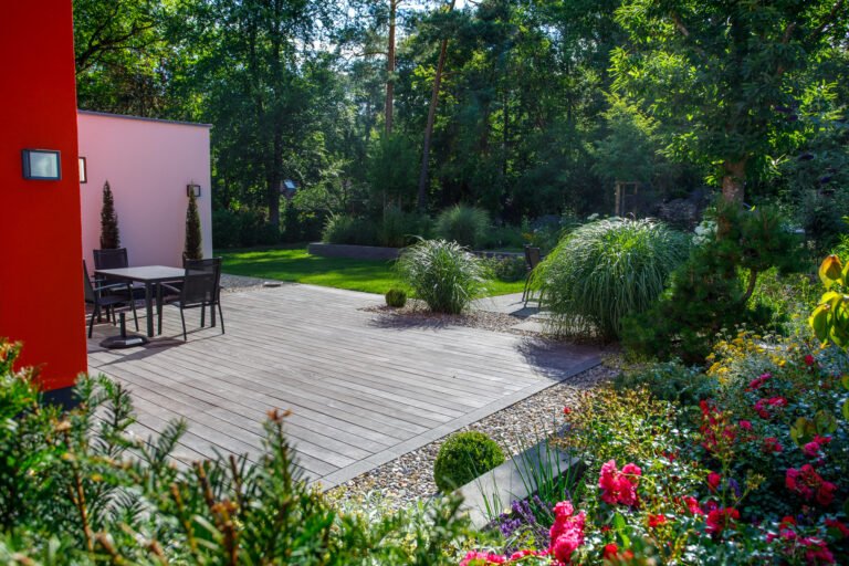 Moderne Holzterrasse mit Sitzbereich, Staudenpflanzung, Ziergräsern und Rasenfläche an einem Wohnhaus, Garten anlegen in Eggolsheim von BELLA FLORA GmbH.