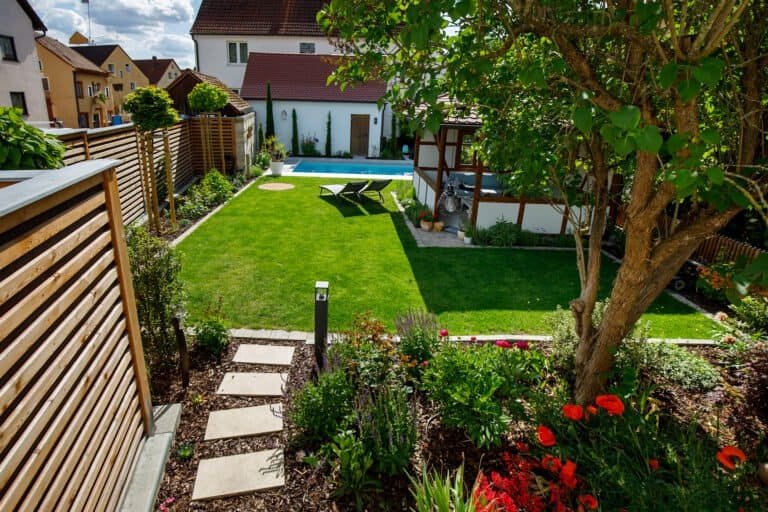 Moderner Wohngarten mit Rasenfläche, Trittplattenweg, Holzsichtschutz und Poolanlage im Innenhof, Garten anlegen in Forchheim von BELLA FLORA GmbH.