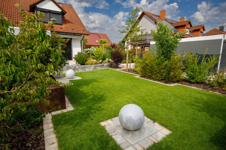 Moderner Privatgarten mit Rasenfläche, Betonsteinmauer und Formschnittgehölzen bei einem Einfamilienhaus, Garten anlegen in Bamberg von BELLA FLORA GmbH.