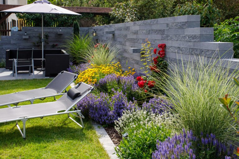 Moderner Garten mit Betonstein-Sichtschutzmauer, Staudenbeet, Rasenfläche und Terrassenbereich als hochwertige Gartengestaltung in Altendorf von BELLA FLORA GmbH.