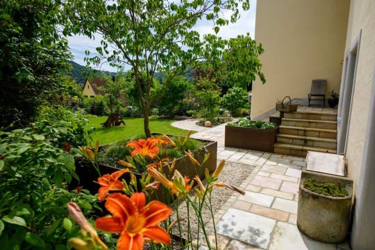 Gartenweg und Terrasse aus Natursteinplatten mit integrierter Treppenanlage, Staudenpflanzung und Solitärbaum als hochwertige Gartengestaltung in Wiesenthau von BELLA FLORA GmbH.