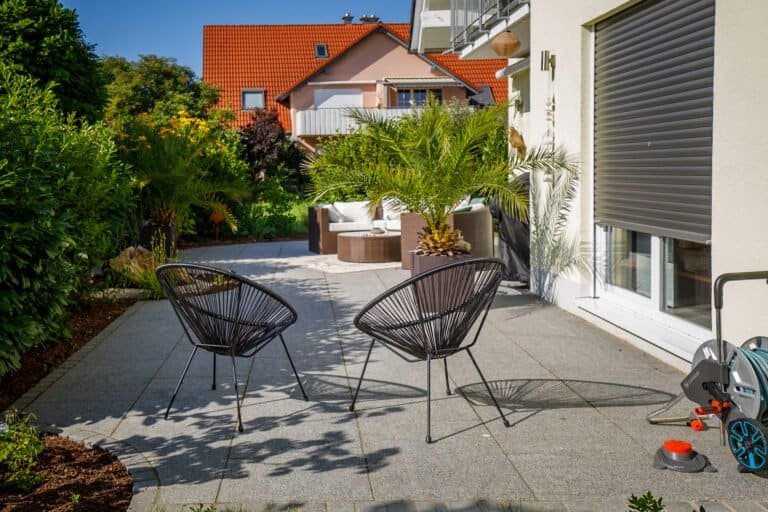 Gartenbau Bamberg, Moderne Terrassenfläche aus großformatigen Granitplatten mit Sitzbereich und integrierter Gartenbepflanzung als hochwertige Terrassengestaltung in Pretzfeld von BELLA FLORA GmbH.
