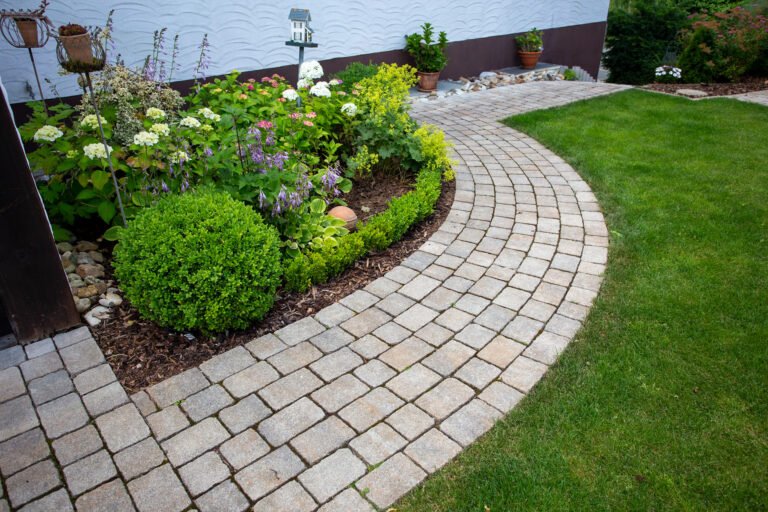 Geschwungener Gartenweg aus Beton-Kleinpflaster mit Beet- und Raseneinfassung, fachgerechte Garten- und Wegebauarbeiten in Bamberg von BELLA FLORA GmbH.