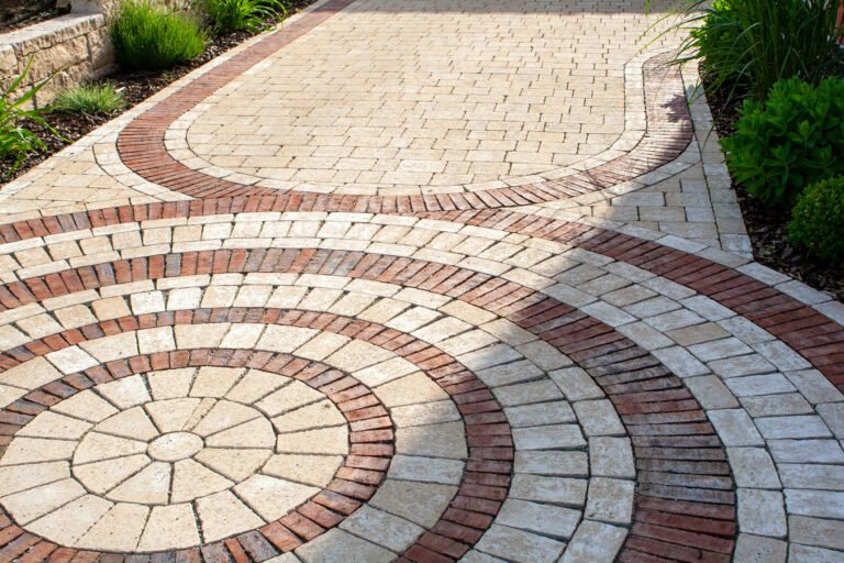 Dekorative Pflasterfläche mit Kreisornament aus Betonpflaster und rotbraunen Klinkerbändern, hochwertige Pflasterarbeiten und Terrassenbau in Pottenstein von BELLA FLORA GmbH.