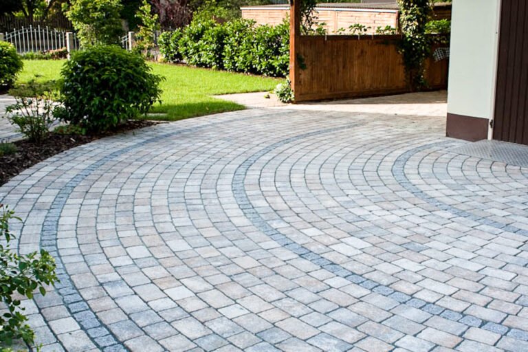 Geschwungene Hofeinfahrt mit hochwertigem Betonpflaster im Segmentbogen-Verband und abgesetzten Pflasterbändern, fachgerechte Pflasterarbeiten und Einfahrtsbau in Gößweinstein von BELLA FLORA GmbH.