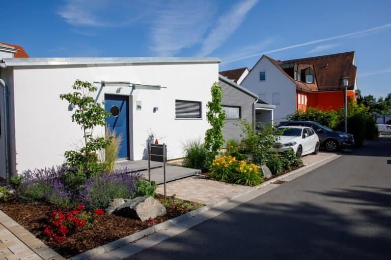 Moderner Vorgarten mit gepflastertem Hauseingang, Staudenbeeten, Ziergräsern und Natursteinakzenten zur professionellen Vorgartengestaltung in Forchheim von BELLA FLORA GmbH.