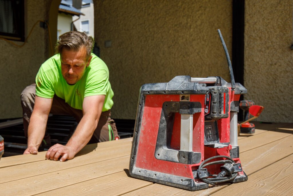 Ausrichten und Montieren von Holzdielen mit Montagegerät beim Terrassenbau im Außenbereich, präzise Holzarbeiten und Terrassenbau in Forchheim von BELLA FLORA GmbH.