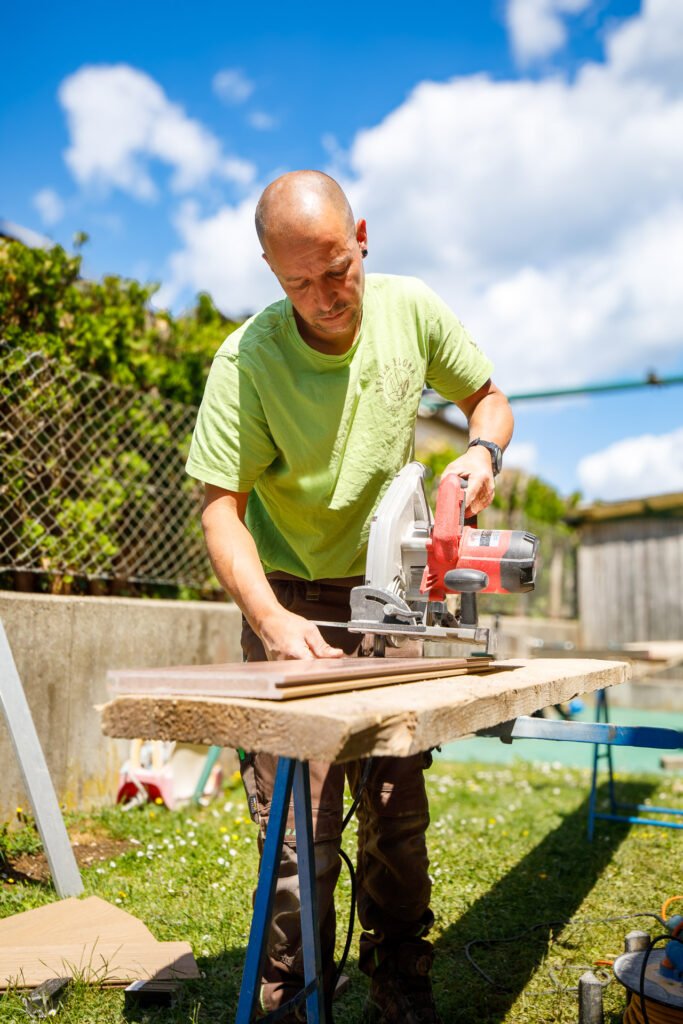Zuschnitt von Holzdielen mit Handkreissäge für Terrassenbau im Außenbereich, präzise Holzarbeiten und Terrassenbau in Bamberg von BELLA FLORA GmbH.