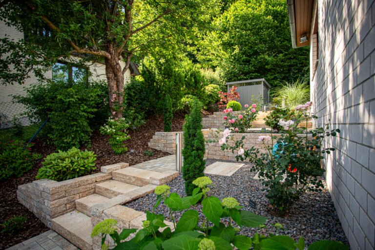 Terrassierte Gartenanlage mit Betonstein-Stützmauern, Blockstufen, Kieswegen und strukturierter Staudenbepflanzung am Wohnhaus, Garten- und Landschaftsbau, Ebermannstadt von BELLA FLORA GmbH.