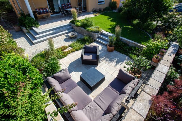 Mehrstufige Gartenanlage mit abgesenkter Lounge-Terrasse, Betonplatten, Betonsteinmauern und Rasenfläche, professionelle Garten- und Terrassengestaltung in Bamberg von BELLA FLORA GmbH.