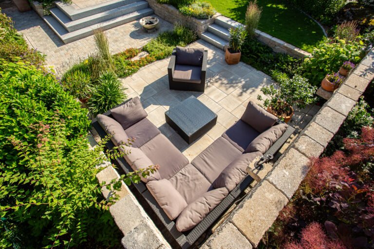 Abgesenkte Terrassenlounge mit Betonplatten, Betonsteinmauer und integrierter Staudenbepflanzung, hochwertige Terrassen- und Gartenanlagen in Bamberg von BELLA FLORA GmbH.