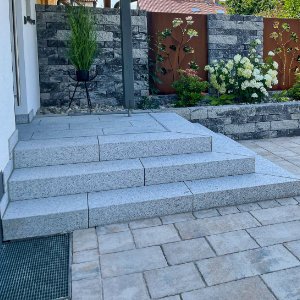 Eingangstreppe aus Granitblockstufen mit angrenzender Pflasterfläche und moderner Gartengestaltung in Pinzberg von BELLA FLORA GmbH.