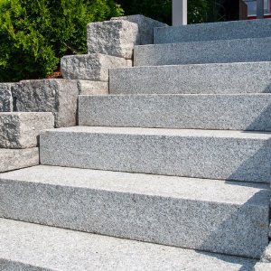 Großformatige Granit-Blockstufen als Außentreppe mit seitlicher Betonsteinmauer in Wiesenthau von BELLA FLORA GmbH.