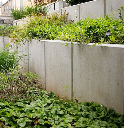 Moderne Beton-Stützmauer mit bepflanzten Terrassenbeeten zur Hangabfangung in zeitgemäßer Gartengestaltung, fachgerechter Mauer- und Erdbau in Hausen von BELLA FLORA GmbH.