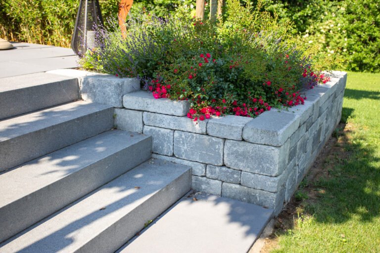 Stützmauer aus Betonstein mit integrierter Treppenanlage und Stauden- sowie Rosenbepflanzung zur Gartengestaltung in Reuth von BELLA FLORA GmbH.