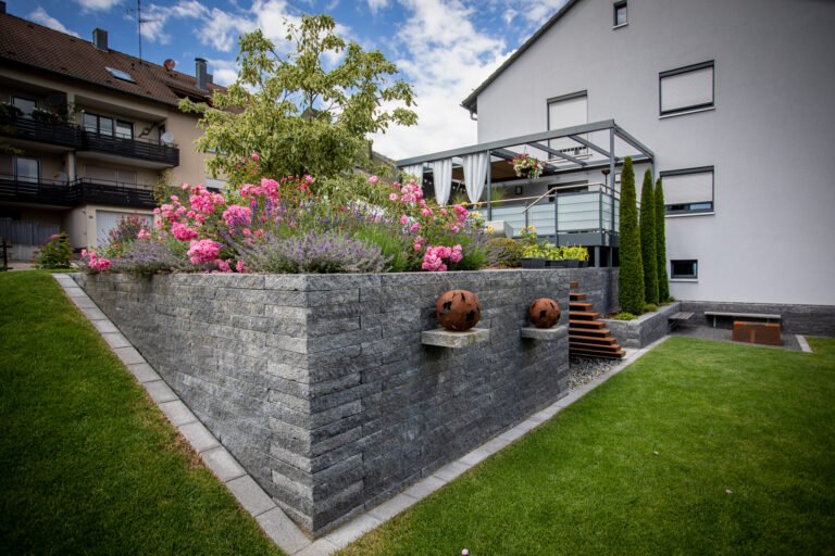 Moderne Betonstein-Stützmauer mit Hochbeet, Staudenpflanzung und integrierter Treppenanlage zur Gartengestaltung in Ebermannstadt von BELLA FLORA GmbH.