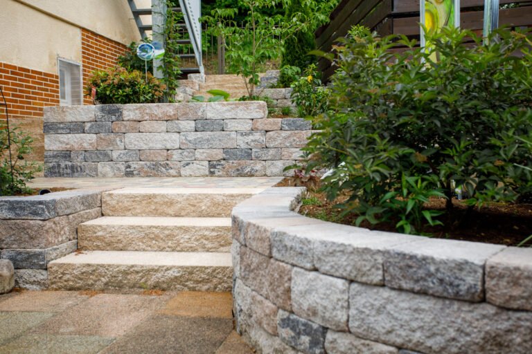 Betonstein-Stützmauer mit integrierter Treppenanlage und Pflasterfläche im Hausgarten, fachgerechter Garten- und Landschaftsbau in Gößweinstein von BELLA FLORA GmbH.