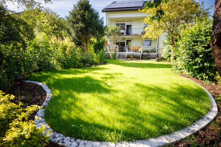 Großzügige Rasenfläche mit geschwungener Einfassung, Terrassenanlage und strukturierter Bepflanzung im Garten- und Landschaftsbau in Weilersbach von BELLA FLORA GmbH.