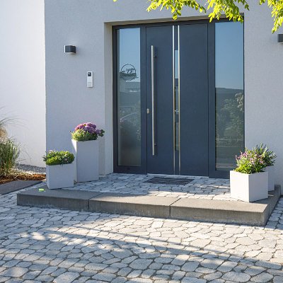 Moderner Hauseingang mit Betonblockstufe, Betonpflaster und formschöner Pflasterfläche als hochwertige Eingangs- und Pflasteranlage in Kersbach von BELLA FLORA GmbH.