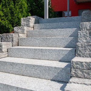 Außentreppe aus Granitblockstufen mit seitlichen Stützmauern aus Betonstein als fachgerechte Treppenanlage in Wiesenttal von BELLA FLORA GmbH.