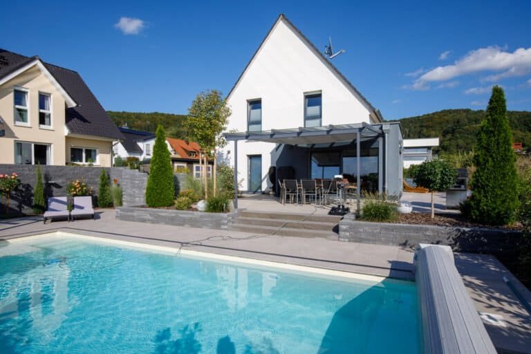 Moderne Poolanlage mit Betonsteinmauern, Stufenanlage und überdachter Terrasse als Garten- und Poolbau in Eggolsheim von BELLA FLORA GmbH.