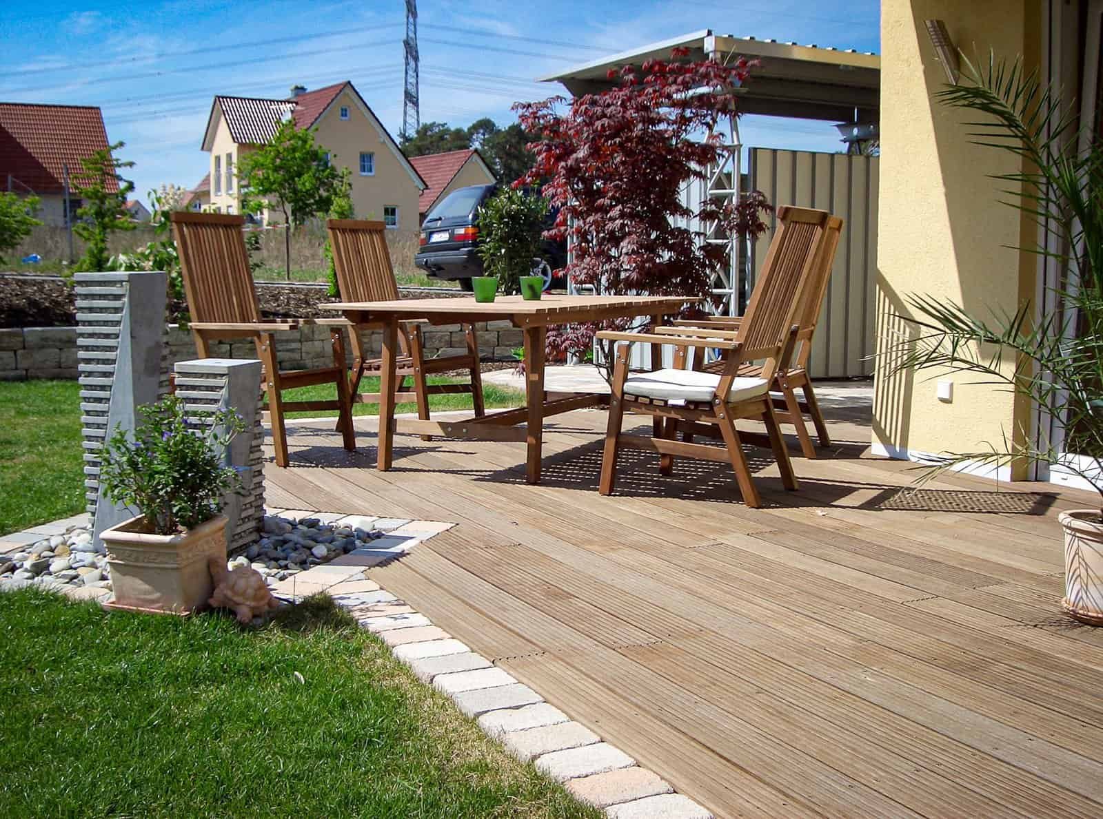 Holzterrasse mit Bangkirai-Dielen, moderner Stele und Rasenanschluss im Privatgarten – Terrassenbau in Hausen von BELLA FLORA GmbH.