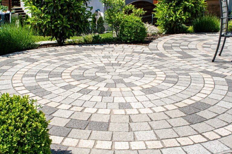 Kreisförmig verlegte Betonpflaster-Terrasse mit mehrfarbigem Muster im Privatgarten – Pflasterarbeiten in Burk von BELLA FLORA GmbH.