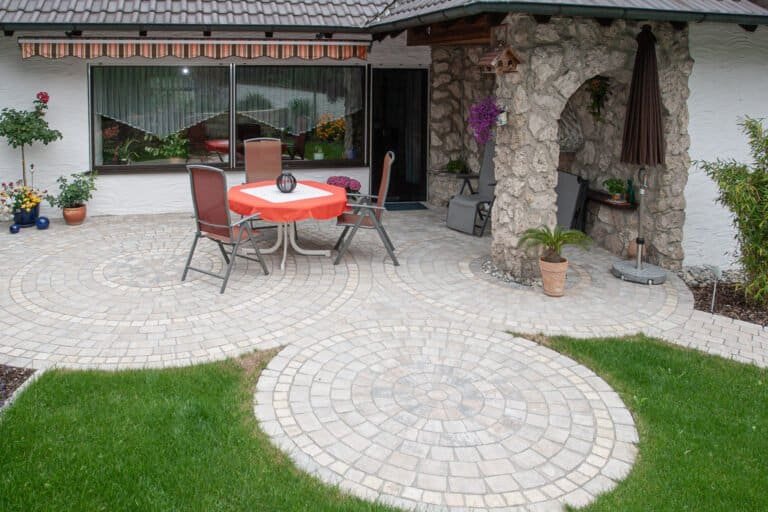 Runde Pflasterterrasse mit Kreisornament und Betonsteinpflaster am Wohnhaus – Pflasterarbeiten in Buckenhofen von BELLA FLORA GmbH.