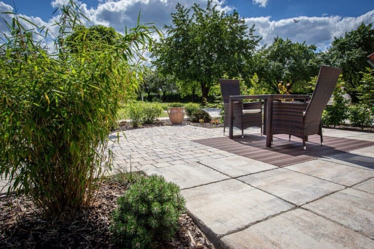 Betonstein-Terrasse mit Sitzplatz, Bambus und Staudenbeet im weitläufigen Privatgarten – Terrassenbau in Wiesenttal von BELLA FLORA GmbH.