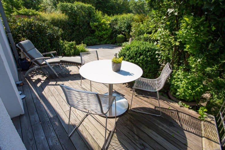 Holzterrasse mit Sitzgruppe und dichter Heckenbepflanzung als Sichtschutz – Terrassengestaltung in Pretzfeld von BELLA FLORA GmbH.