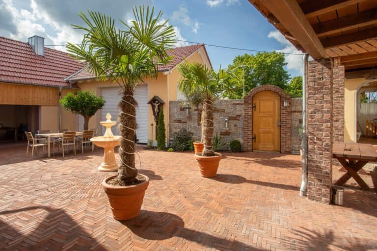 Großzügig gepflasterter Innenhof mit Klinkerpflaster im Fischgrätverband und mediterraner Bepflanzung – Hofgestaltung in Kersbach von BELLA FLORA GmbH.