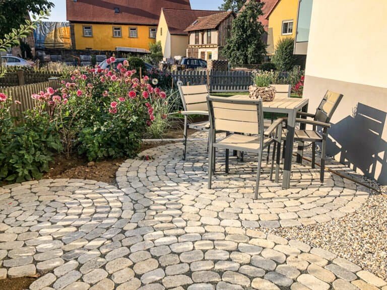 Rund verlegte Betonpflaster-Terrasse mit geschwungenem Muster und Staudenbeet – Pflasterarbeiten in Reuth von BELLA FLORA GmbH.